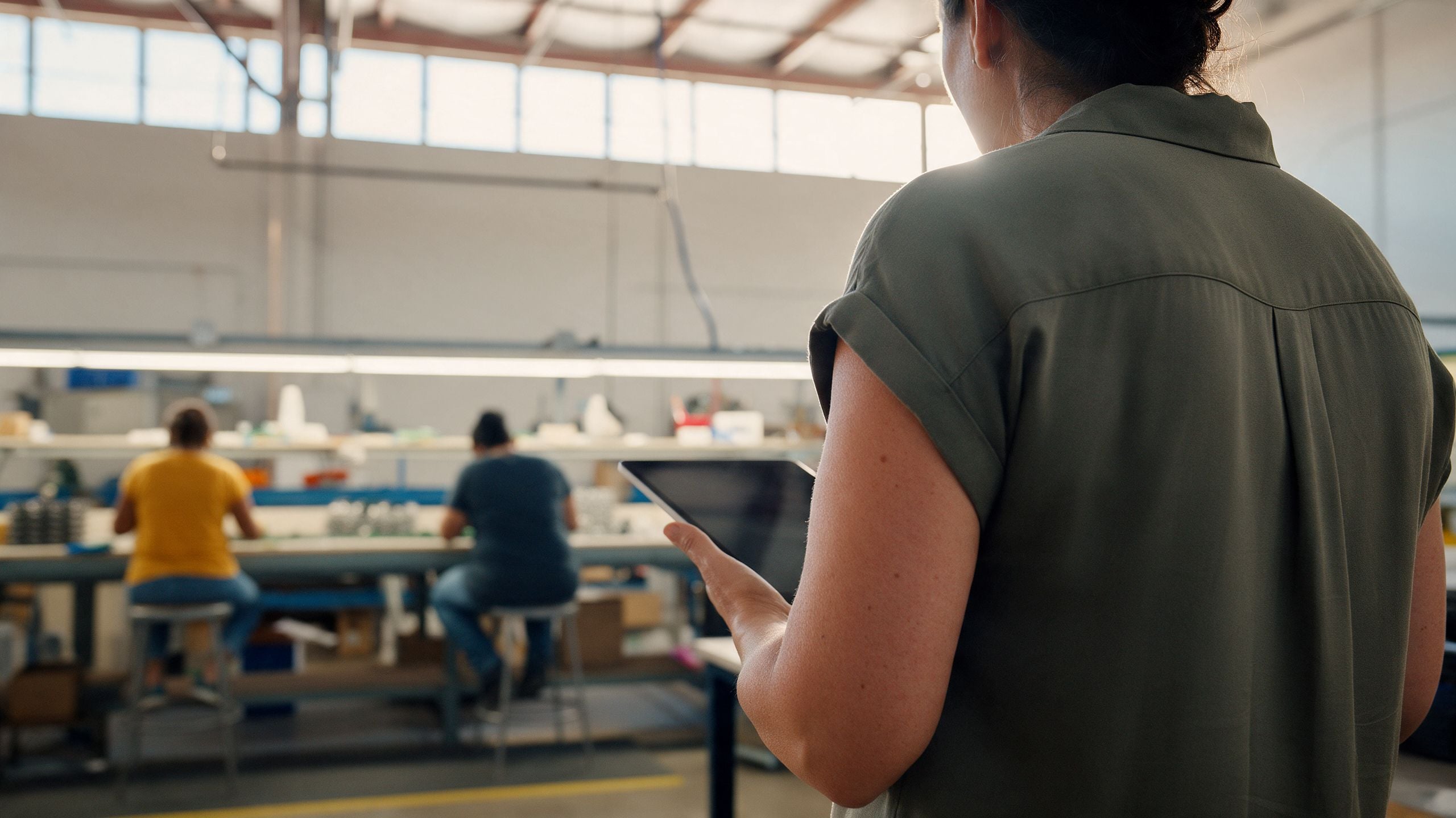 Operations manager overseeing a small manufacturing floor in Tucson, Arizona, seen from behind.